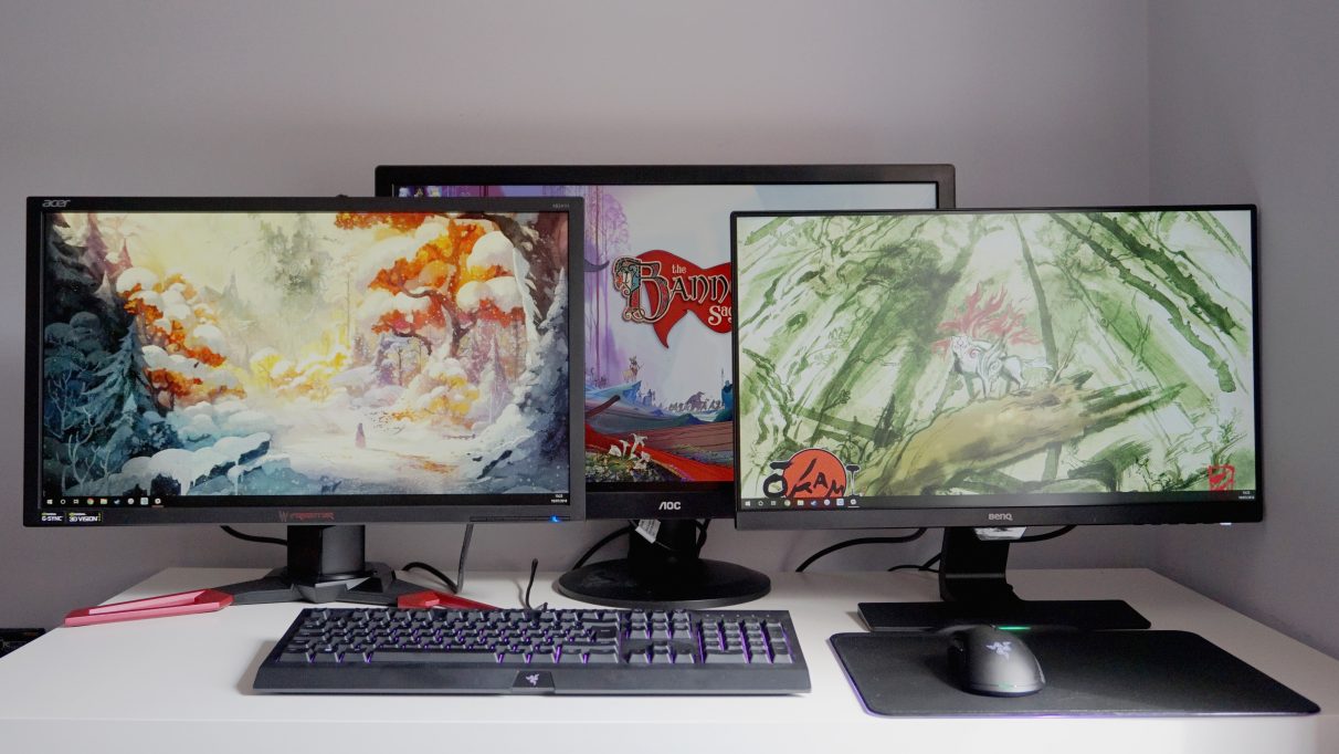 A photo of three gaming monitors on a table.